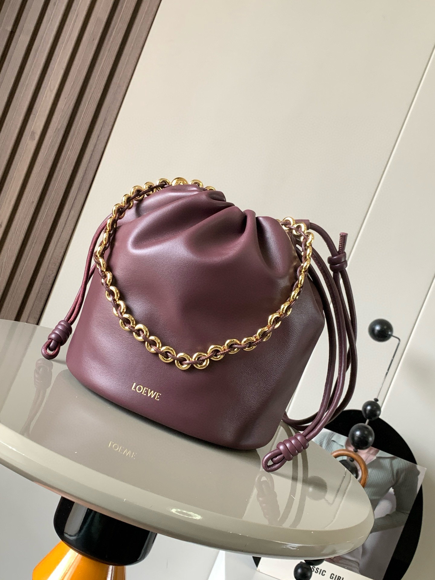 新款柔软纳帕羊皮革 Flamenco Purse Bucket 水桶手袋新品 Flamenco Purse 手袋采用褶皱设计 侧面搭配标志性绳结等关键细节Bucket 水桶手袋推出适合日常使用的全新尺寸 同时保留此系列的柔美风格 款式时尚百搭 可搭配甜甜圈链条肩背 或搭配皮革肩带斜挎 此版本采用柔软纳帕羊皮革制成  可肩背 斜挎或手提 可拆卸可调节皮革肩带  可拆卸甜甜圈链条饰有 Anagram 镌刻卵石纹 低调的磁扣开合 绒面革衬里  L O E WE 烫金或烫银 尺寸 32cm 17cm 24cm款号 9062颜色 勃良地红