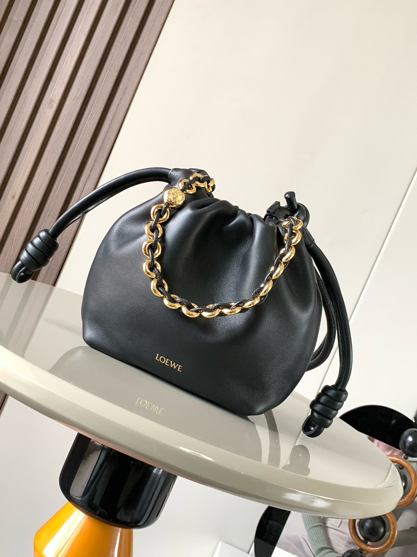   明星同款 迷你纳帕羊皮革 Flamenco Purse 新款手拿包 Flamenco Purse 手袋采用褶皱设计 侧面搭配标志性绳结等关键细节 款式时尚百搭 可作为手拿包携带 亦可搭配甜甜圈 链条肩背或搭配皮革肩带斜挎  此版本采用柔软纳帕羊皮革制成  可肩背 斜挎或手提 可拆卸可调节皮革肩带 可拆卸甜甜圈链条饰有 Anagram 镌刻卵石纹 低调的磁扣开合 绒面革衬里    LOEWE 烫金或烫银 款号 9058尺寸 23cm 17cm 5.5cm颜色 黑色