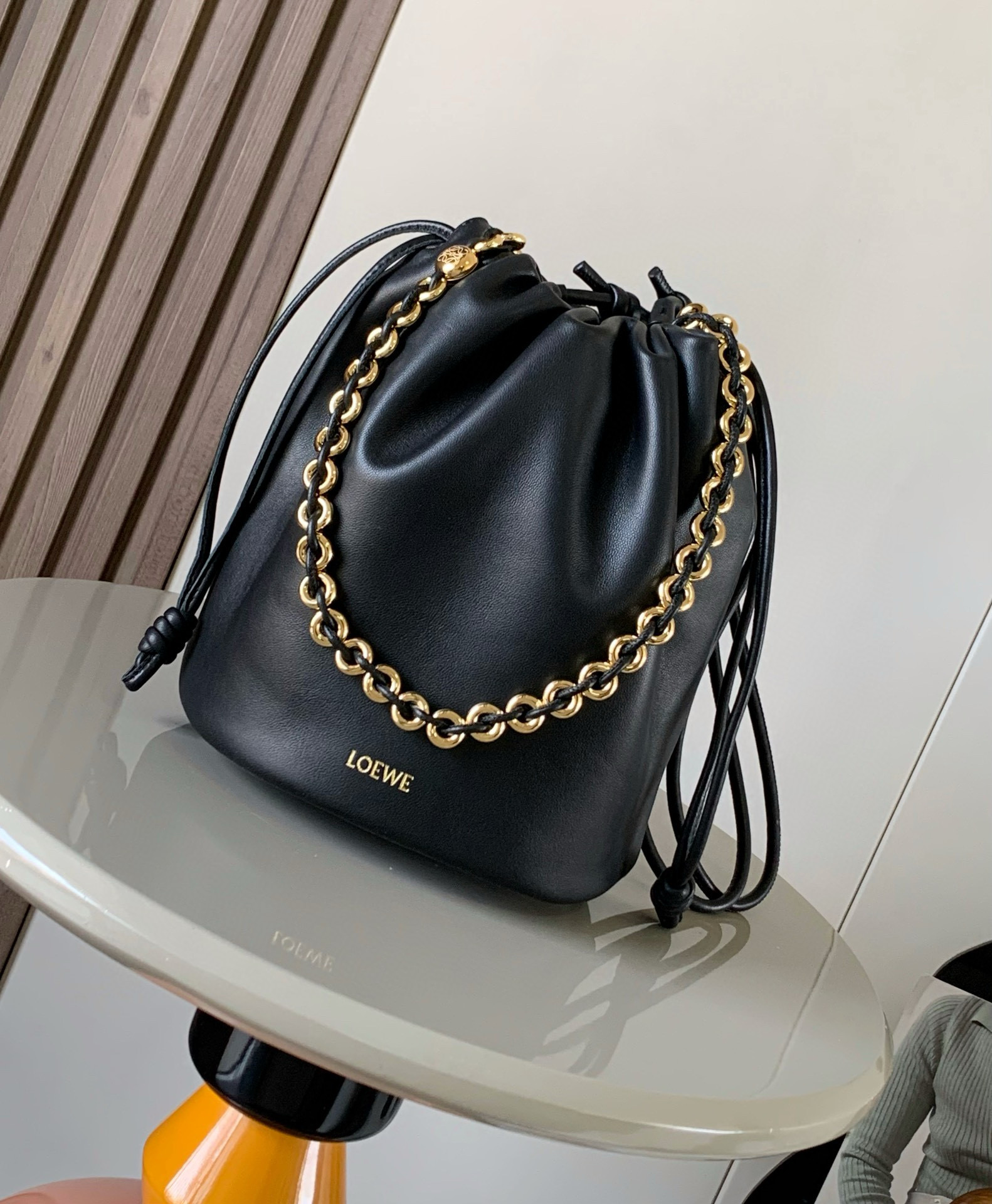 新款柔软纳帕羊皮革 Flamenco Purse Bucket 水桶手袋新品 Flamenco Purse 手袋采用褶皱设计 侧面搭配标志性绳结等关键细节Bucket 水桶手袋推出适合日常使用的全新尺寸 同时保留此系列的柔美风格 款式时尚百搭 可搭配甜甜圈链条肩背 或搭配皮革肩带斜挎 此版本采用柔软纳帕羊皮革制成  可肩背 斜挎或手提 可拆卸可调节皮革肩带  可拆卸甜甜圈链条饰有 Anagram 镌刻卵石纹 低调的磁扣开合 绒面革衬里  L O E WE 烫金或烫银 尺寸 32cm 17cm 24cm款号 9062颜色 黑色