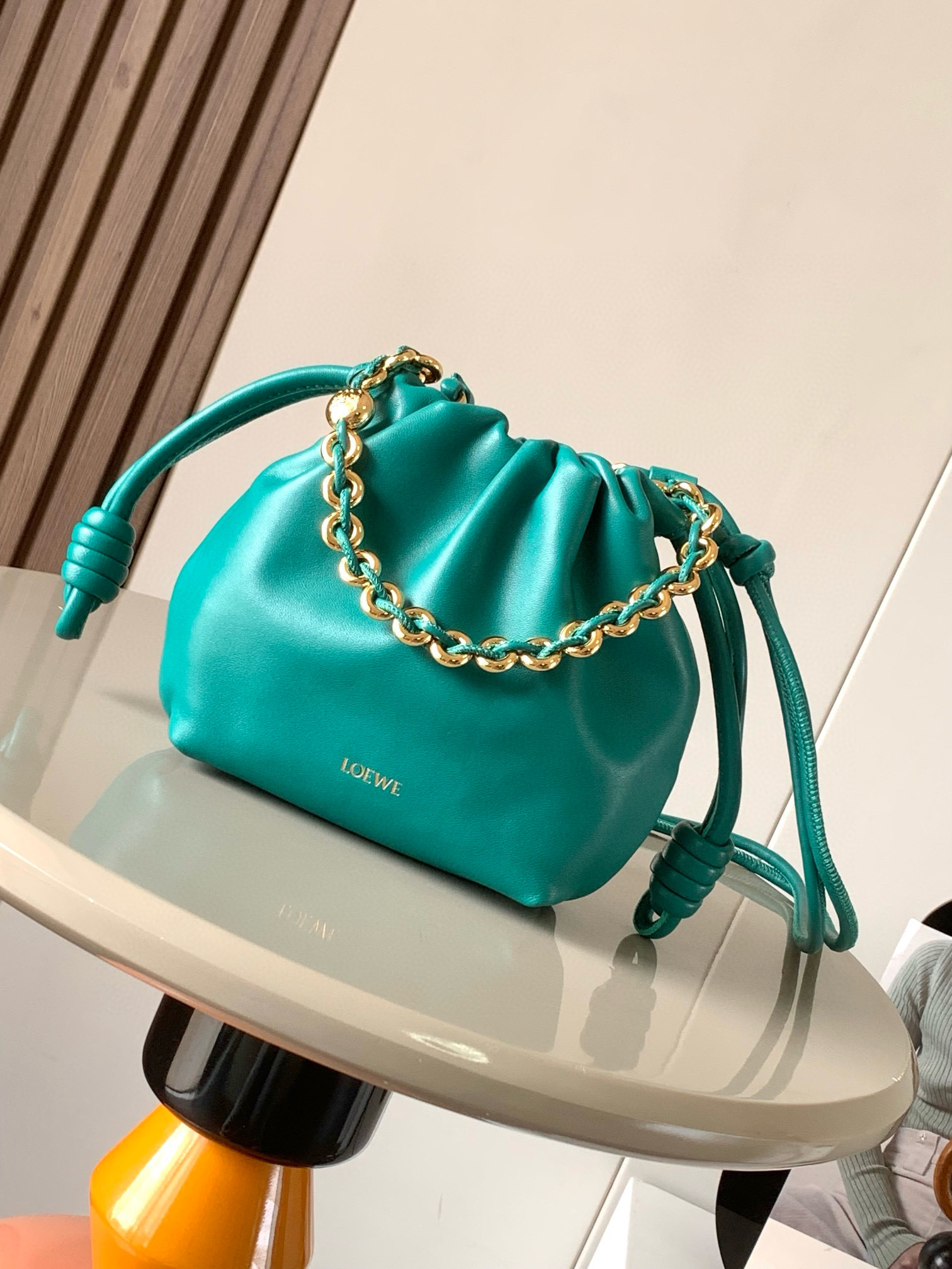   明星同款 迷你纳帕羊皮革 Flamenco Purse 新款手拿包 Flamenco Purse 手袋采用褶皱设计 侧面搭配标志性绳结等关键细节 款式时尚百搭 可作为手拿包携带 亦可搭配甜甜圈 链条肩背或搭配皮革肩带斜挎  此版本采用柔软纳帕羊皮革制成  可肩背 斜挎或手提 可拆卸可调节皮革肩带 可拆卸甜甜圈链条饰有 Anagram 镌刻卵石纹 低调的磁扣开合 绒面革衬里    LOEWE 烫金或烫银 款号 9058尺寸 23cm 17cm 5.5cm颜色 翡翠绿